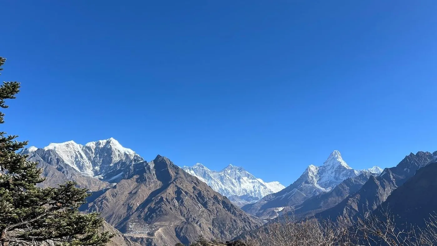 A snow-capped Himalayan range with terraced slopes and a village below, seen from the air